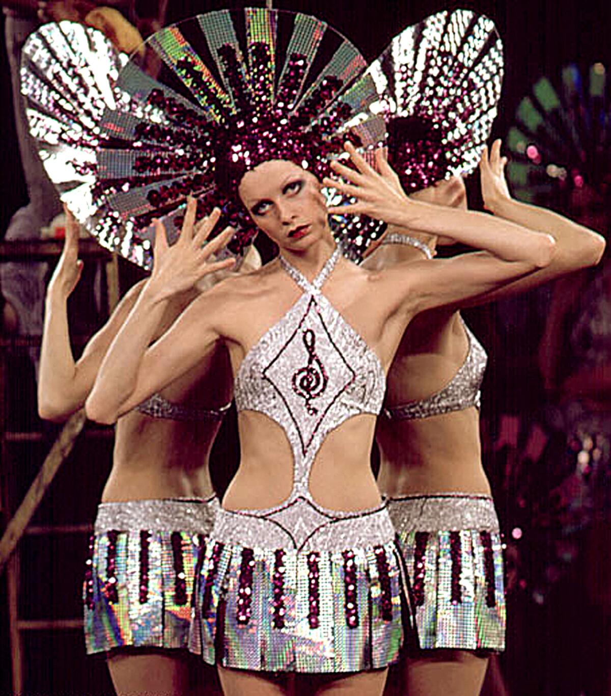 A woman in an elaborate musical costume and headwear strikes a pose.