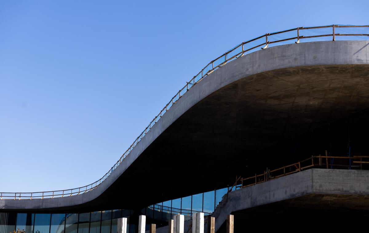 A curved concrete structure with a railing along its top edge and windows underneath