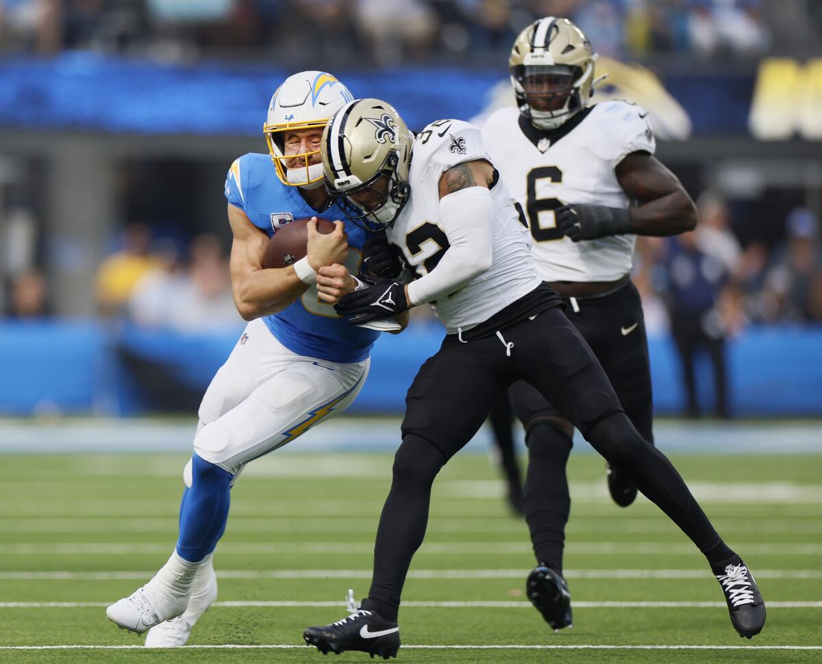 Chargers quarterback Justin Herbert (10) takes a big hit from Saints safety Tyrann Mathieu.