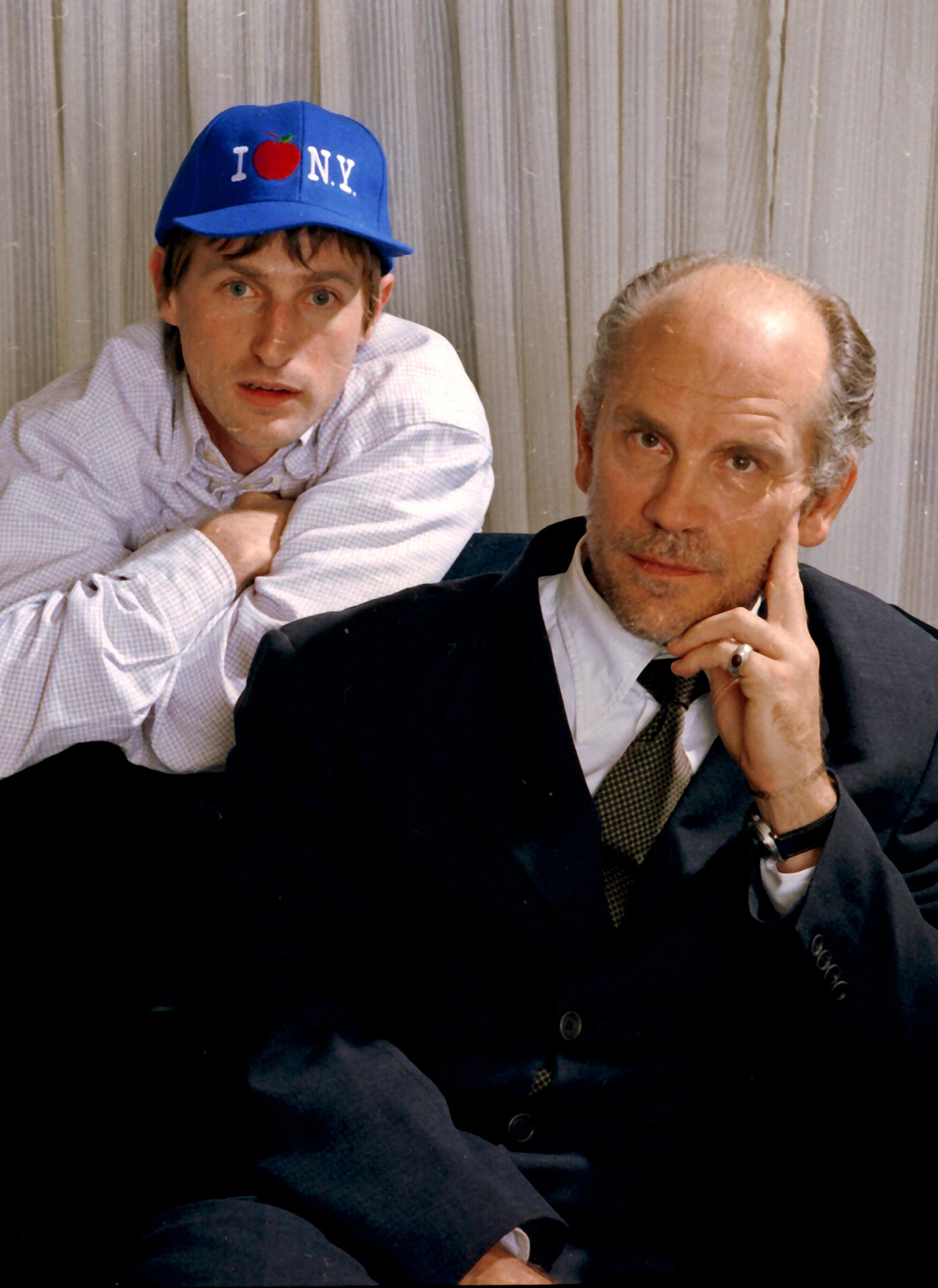 Spike Jonze stands behind and leans on John Malkovich 