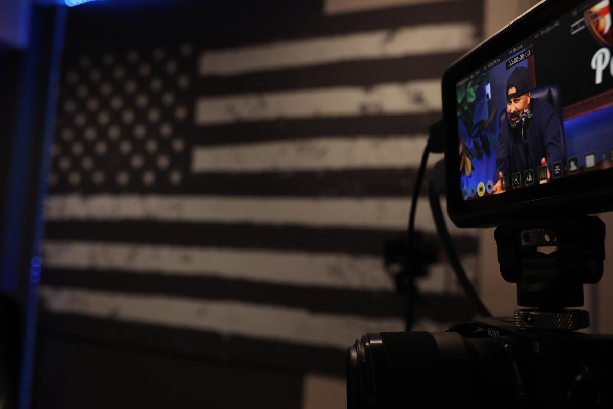 A U.S. flag and a camera monitor showing a man