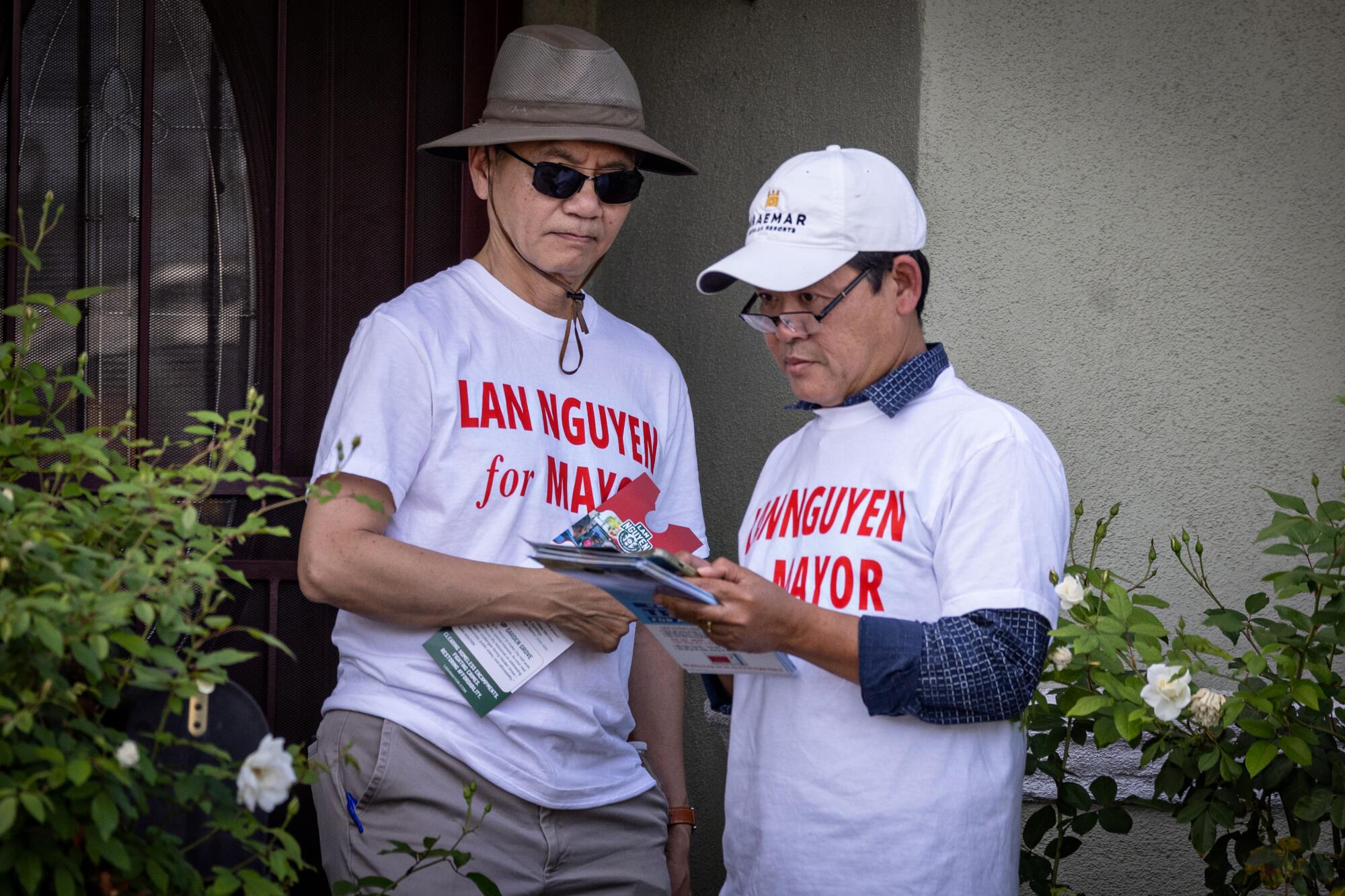 Two people outside a home in "Lan Nguyen for Mayor" T-shirts.