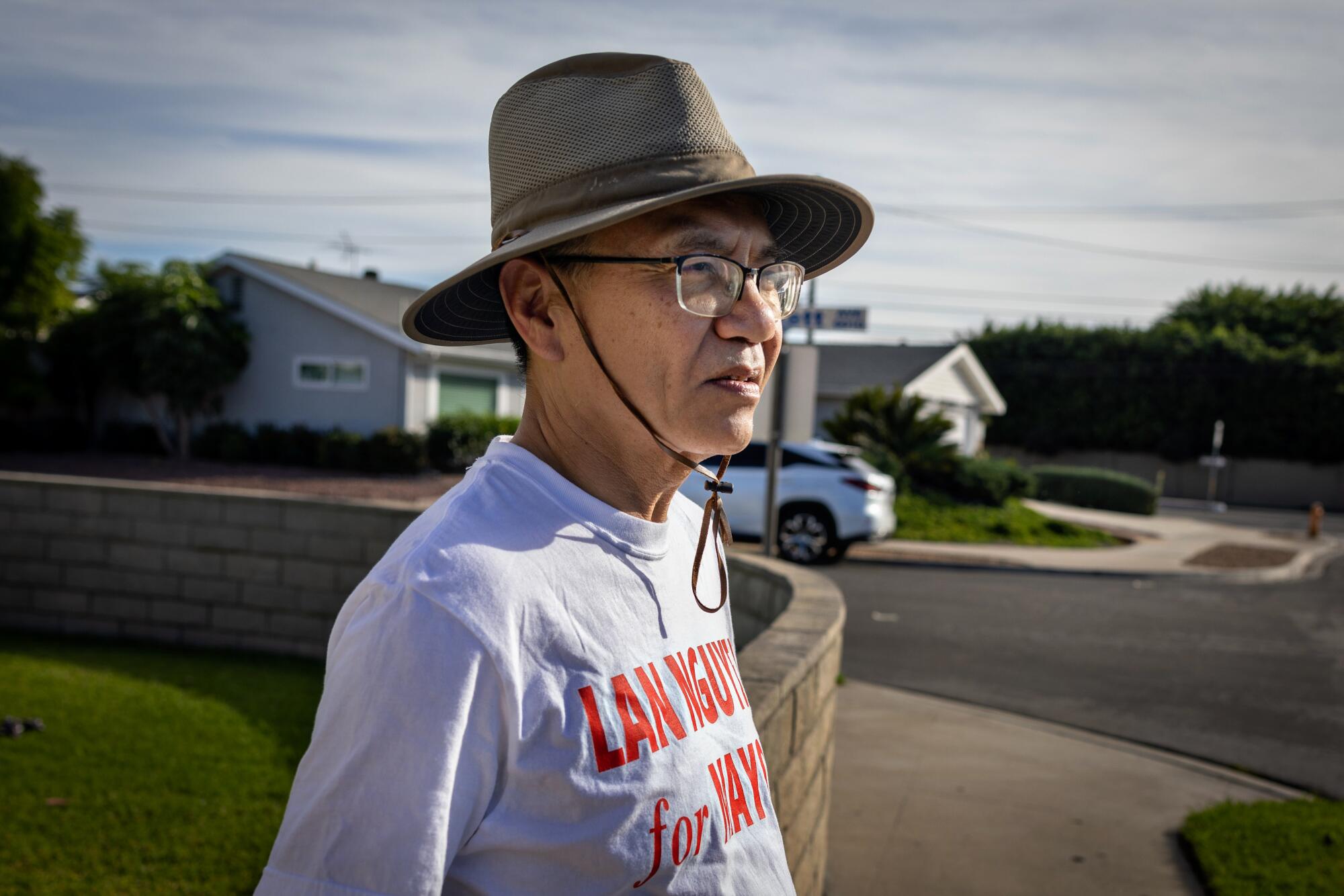 Lan Nguyen stands in a neighborhood wearing a campaign T-shirt.