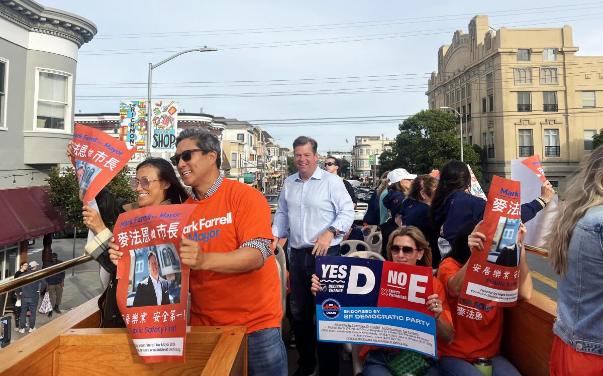 Mayoral candidate Mark Farrell stands on top of a trolley bus with supporters 