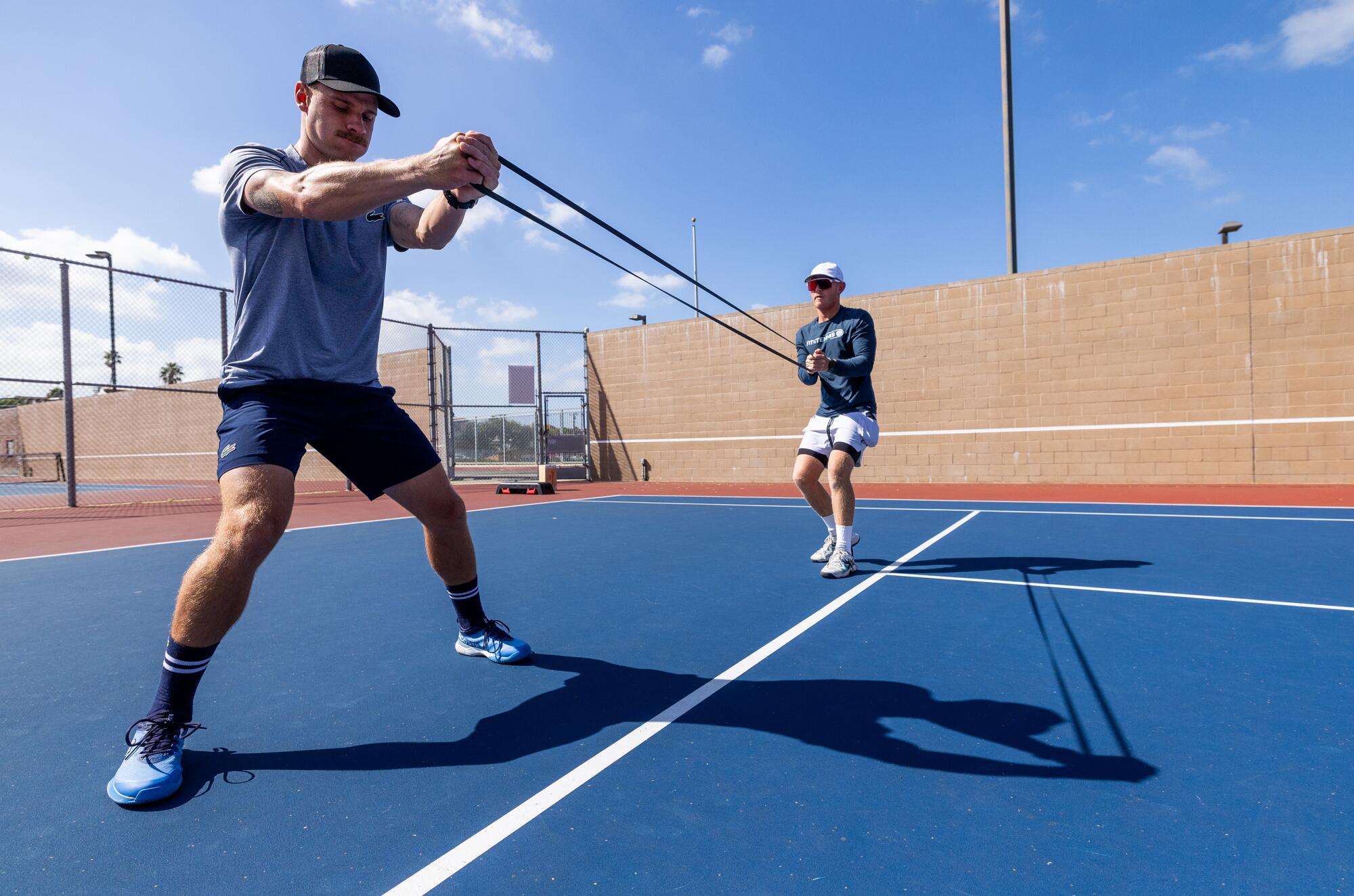 Karue Sell stretches a training band with coach Andrew Mateljan on the courts at Redondo Union High School.