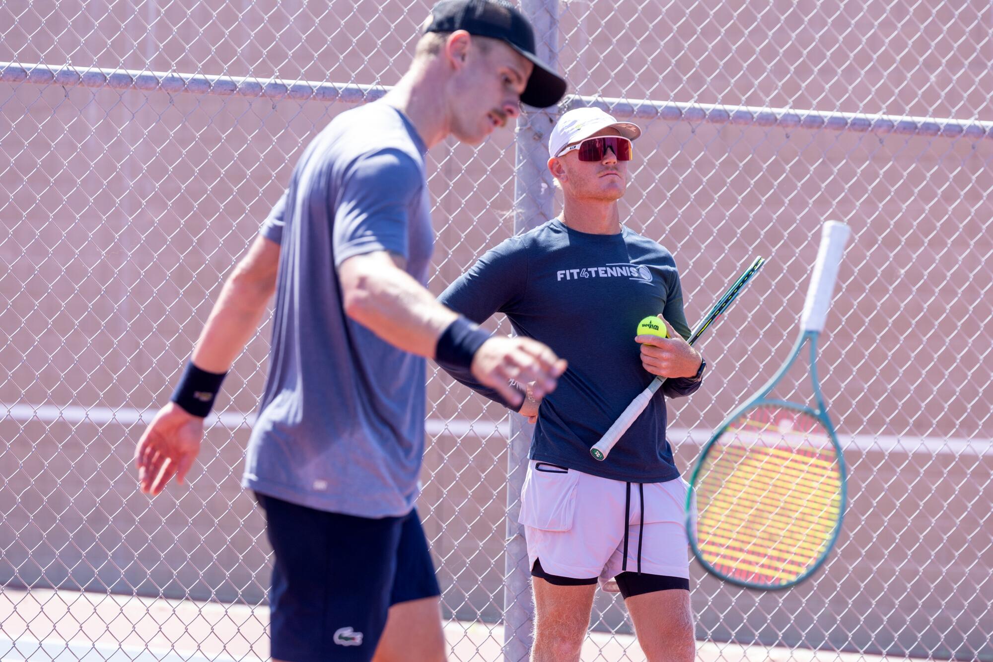 Tennis coach Andrew Mateljan, right, watches as Karue Sell tosses his racket in frustration.