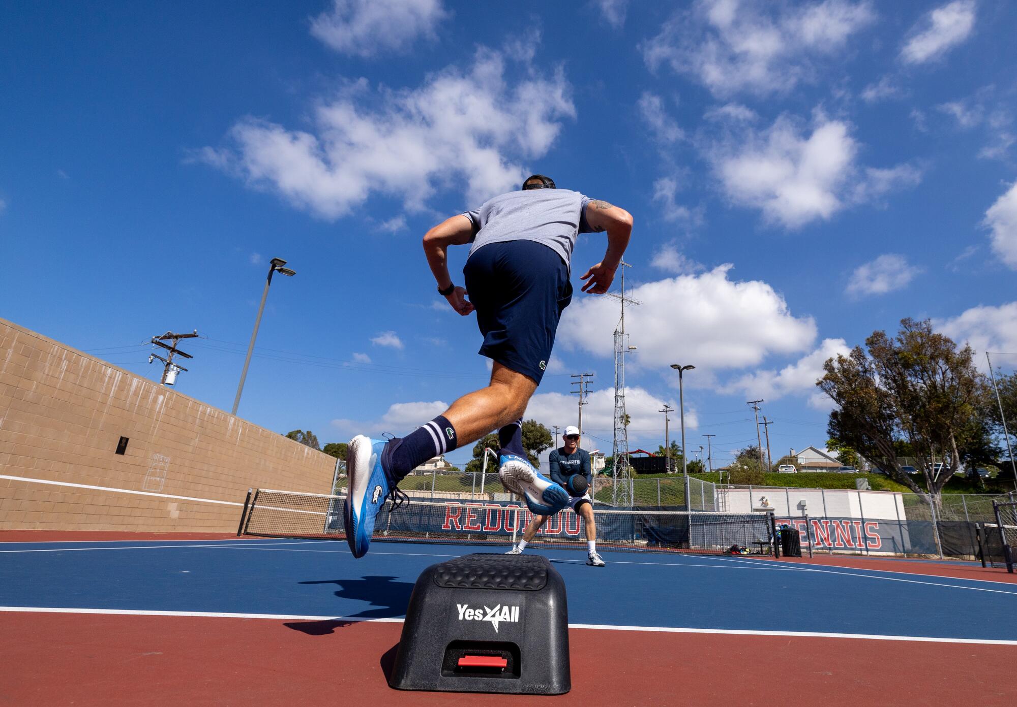 Tennis pro Karue Sell jumps during drills with coach Andrew Mateljan, right, on the courts at Redondo Union High School.