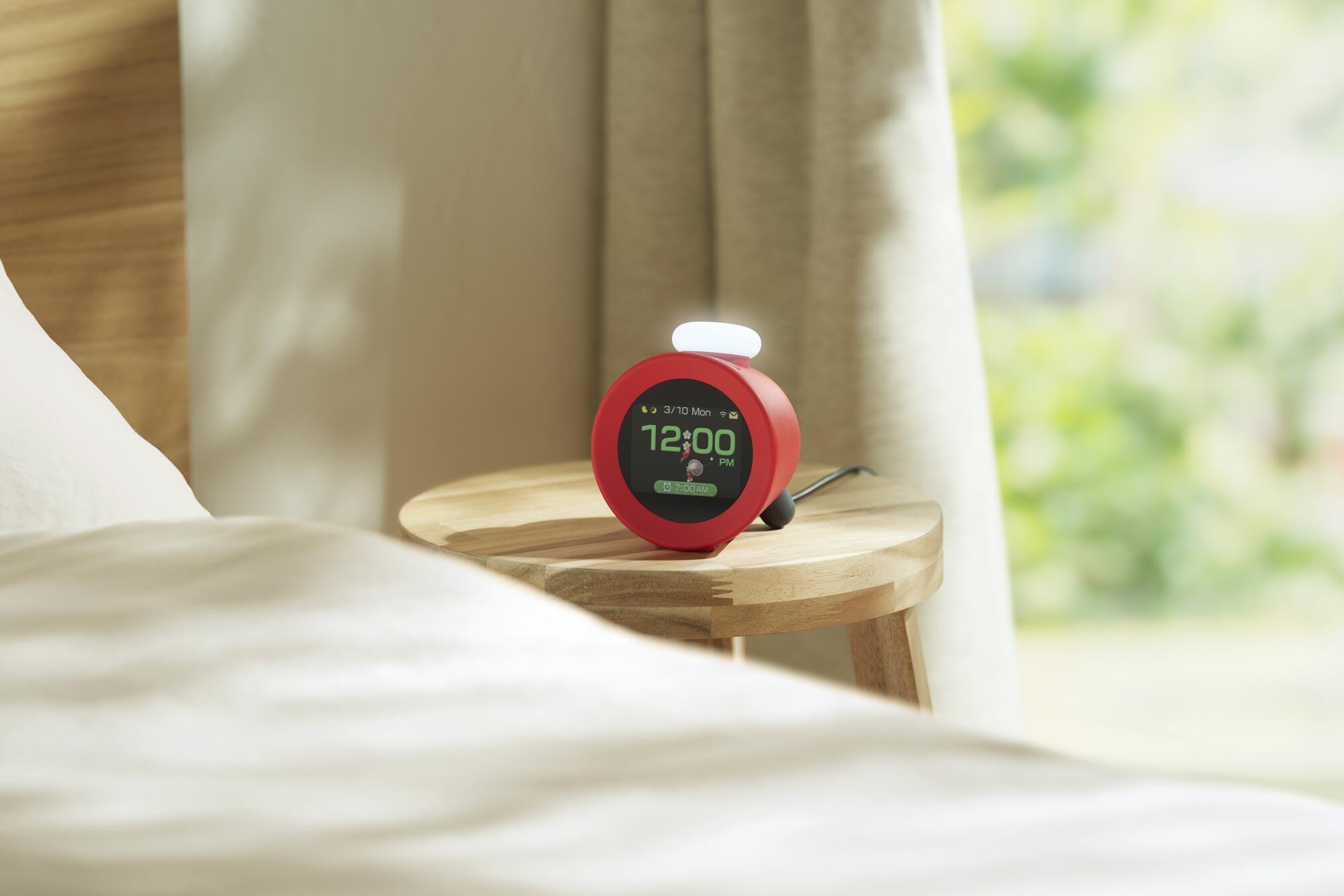 A red alarm clock on a stool.