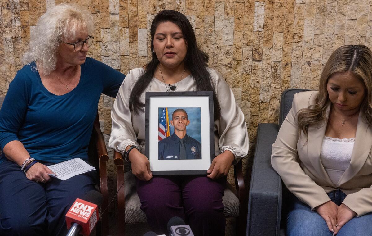 Maria Johnson comforts Angela Mendoza, center, as she holds a portrait of her late boyfriend, LAPD Officer Fernando Arroyos.