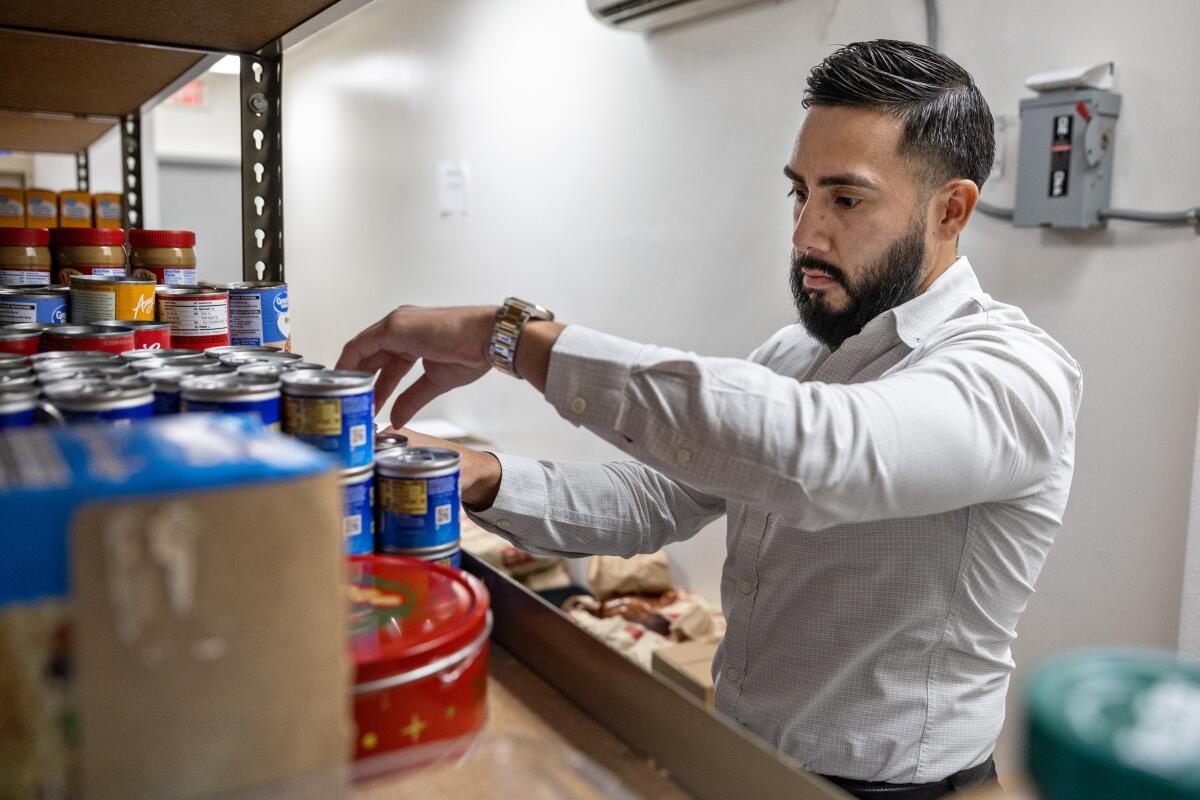 A man looks over canned food on shelves.