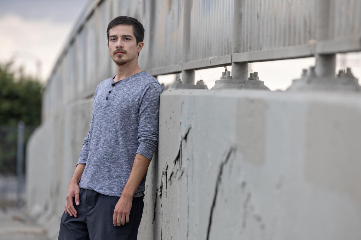 A man with one sleeve pushed up least against a concrete wall.