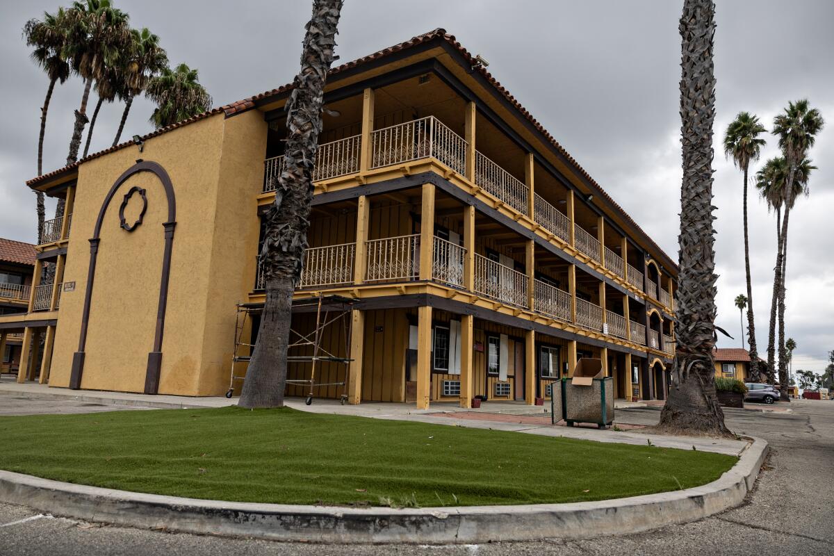 A hotel is surrounded by a virtually empty parking lot. 