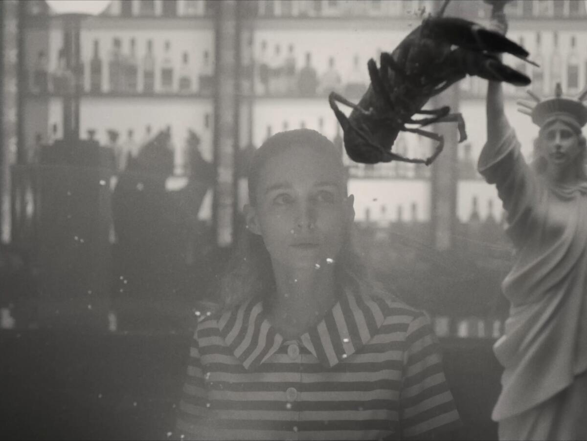 A woman looks in a lobster tank.