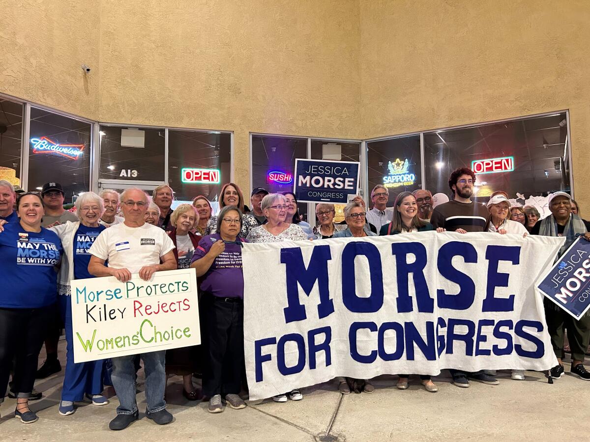 Jessica Morse holds a "Morse for Congress" sign alongside supporters.