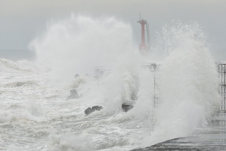 Waves crashing onto a sea wall in Khaosiung. A red-coloured observation post at the end of the wall can just be seen through the water and seaspray