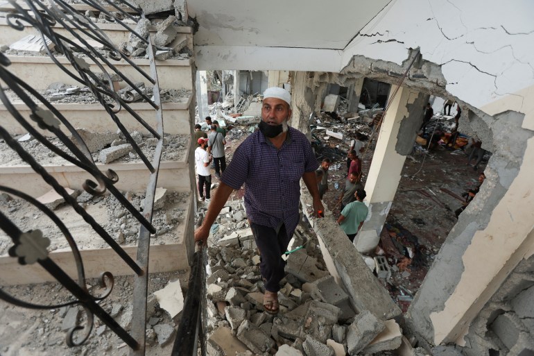 Palestinians inspect the site of an Israeli strike on a mosque sheltering displaced people, amid Israel-Hamas conflict, in Deir Al-Balah, in the central Gaza Strip, October 6