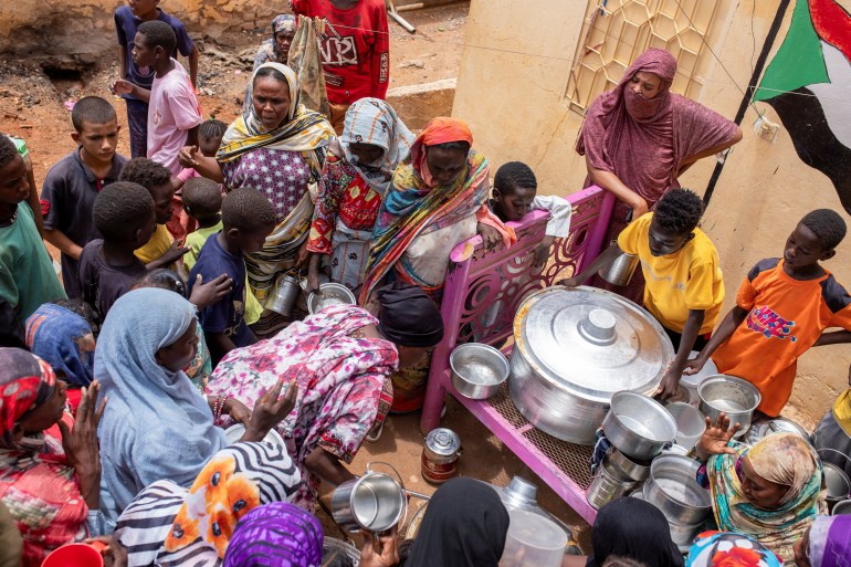 Sudanese women from community kitchens run by local volunteers distribute meals