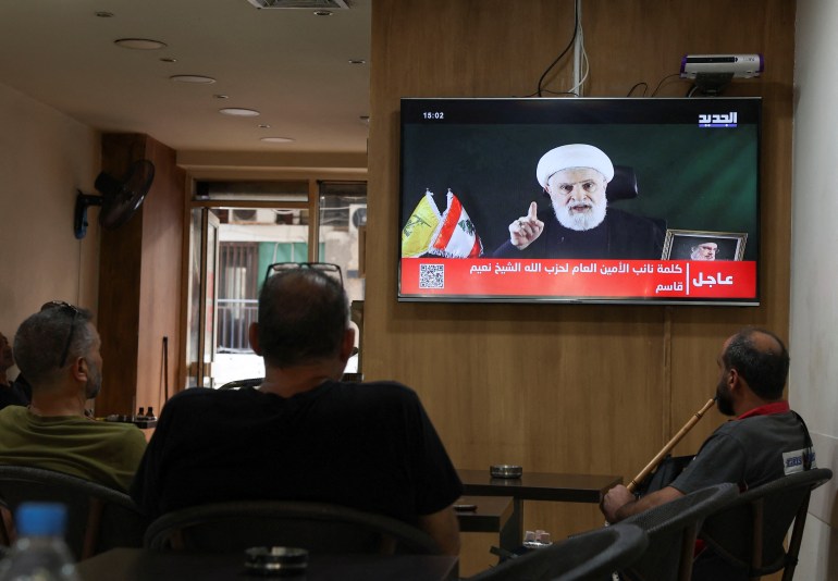 People watch Hezbollah deputy leader Sheikh Naim Qassem delivering a televised address, as they sit in a cafe in Beirut, Lebanon October 15, 2024. REUTERS/Mohamed Azakir