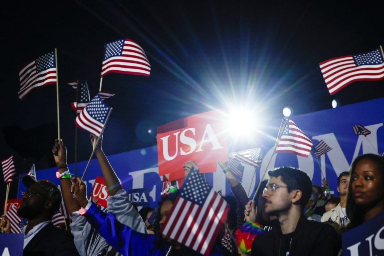 Supporters at a Kamala Harris rally in Washington, DC, wave US flags and hold up "USA" signs.