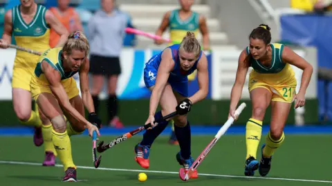 PA Media Scotland's Morag McLellan, in blue kit is tackled by Australia's Casey Eastham and Jayde Taylor, in yellow and green kit, during the Womens Pool Hockey match at the National Hockey Centre, during the 2014 Commonwealth Games in Glasgow.