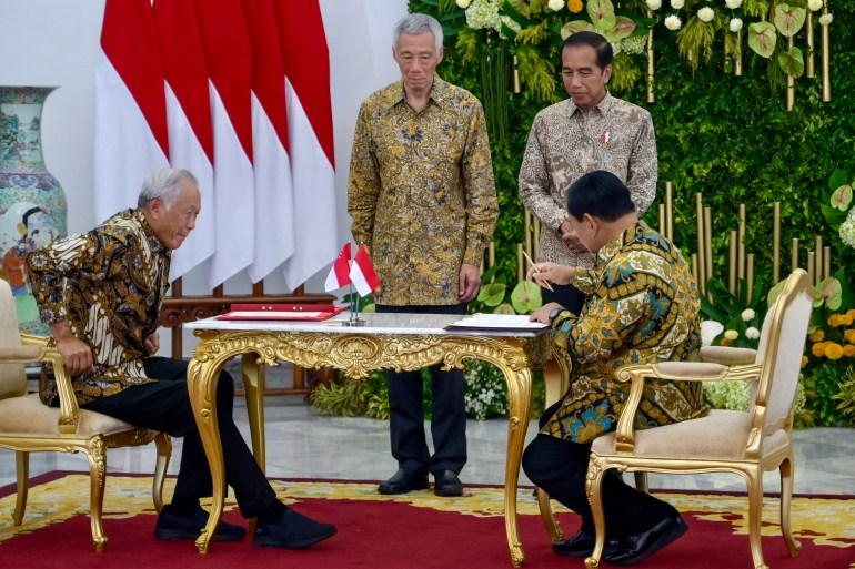 Singapore's outgoing Prime Mnister Lee Hsien Loong wearing batik on a visit to Indonesia. He is standng next to President Joko Widodo. In front of them the two countries defence ministers are signing documents. All are wearing batik.