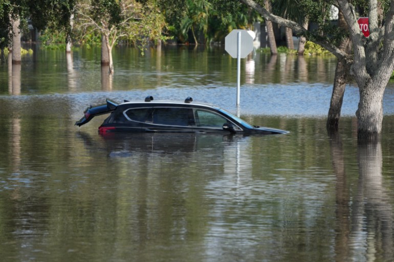 A car is flooded in an apartment complex in Clearwater, Florida, following the passage of Hurricane Milton on October 10, 2024. - At least 10 people were dead after Hurricane Milton smashed into Florida, US authorities said Thursday, after the monster weather system sent tornados spinning across the state and flooded swaths of the Tampa Bay area. (Photo by Bryan R. SMITH / AFP)