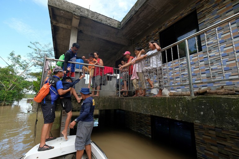 Rescuers evacuate a family from their submerged house brought about from Tropical Storm Trami in Bula town, Camarines Sur province, South of Manila on October 26, 2024. In the hard-hit Bicol region, residents trapped on the roofs and upper floors of their homes were still awaiting desperately needed assistance, officials told AFP. (Photo by ZALRIAN SAYAT / AFP)