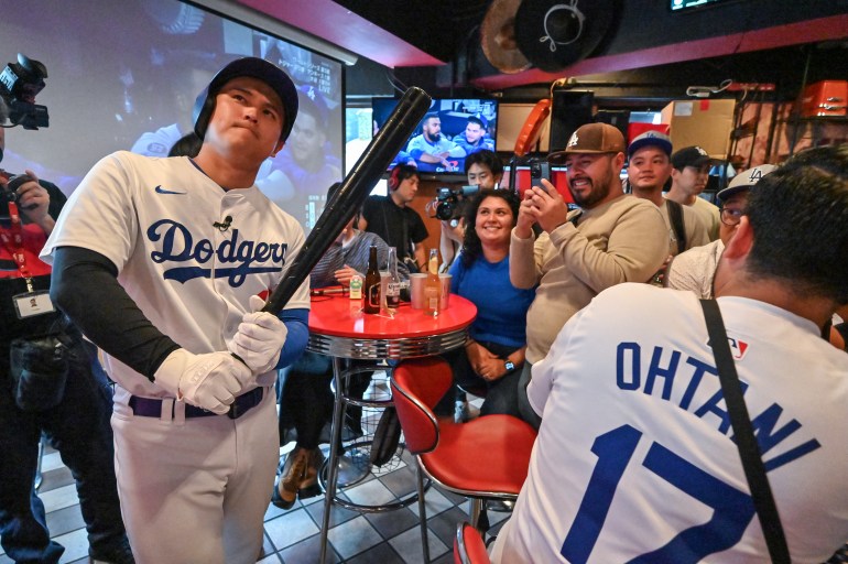 A Shohei Ohtani impersonator (L) poses with a bat at a bar in the Shibuya district of Tokyo on October 31, 2024, during a live broadcast of Game 5 of the US Major League Baseball World Series between the Los Angeles Dodgers and the New York Yankees in New York. (Photo by Richard A. Brooks / AFP)