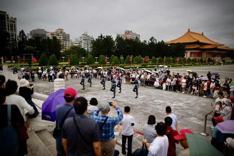 People observe the changing of the honor guard in front of Chiang Kai-shek Memorial Hall in Taipei's Liberty Square on Tuesday after Chinese forces staged live-fire drills just 65 miles away off Niushan Island in the Taiwan Strait. Photo by Ritchie B. Tongo/EPA-EFE