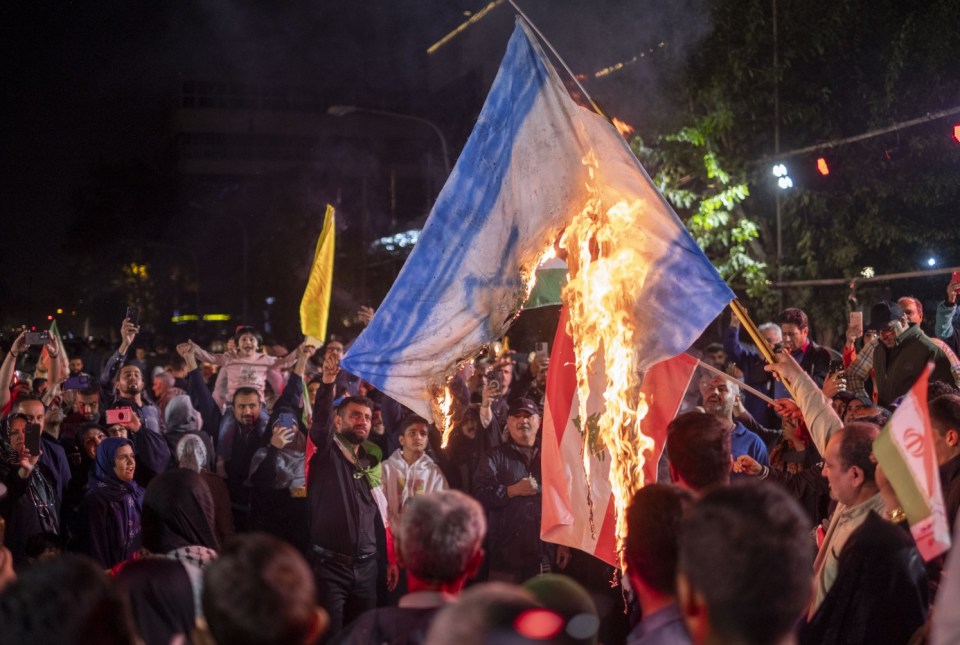 Iranian protesters line the streets as they burn the Israeli flag