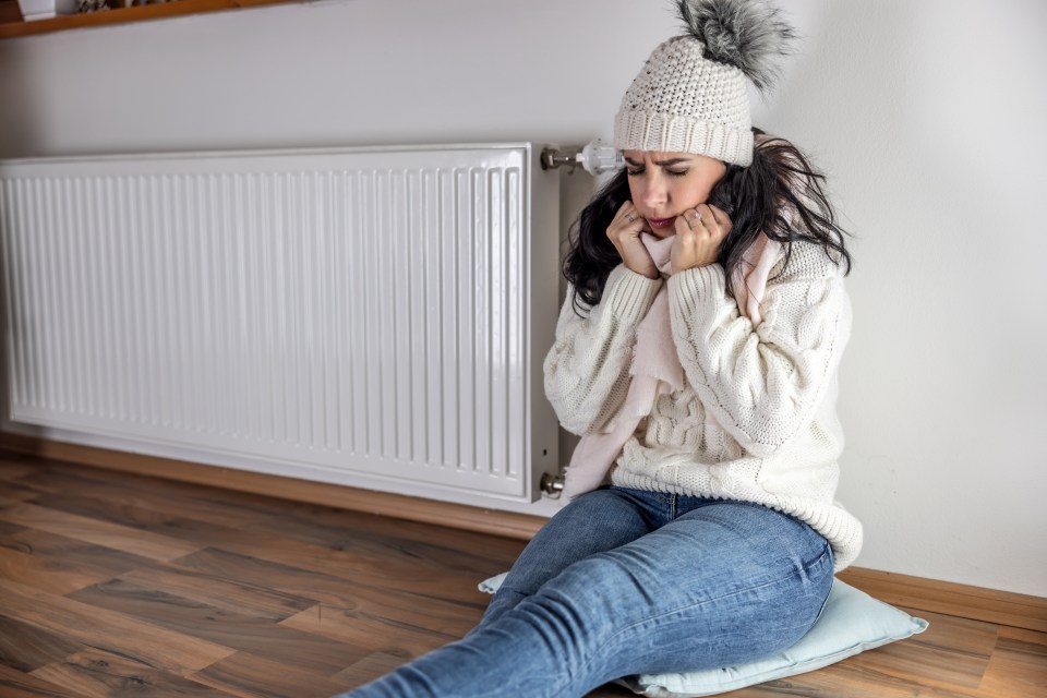 Hypothermic woman sitting by a cold radiator, no heat energy due to Blackout.