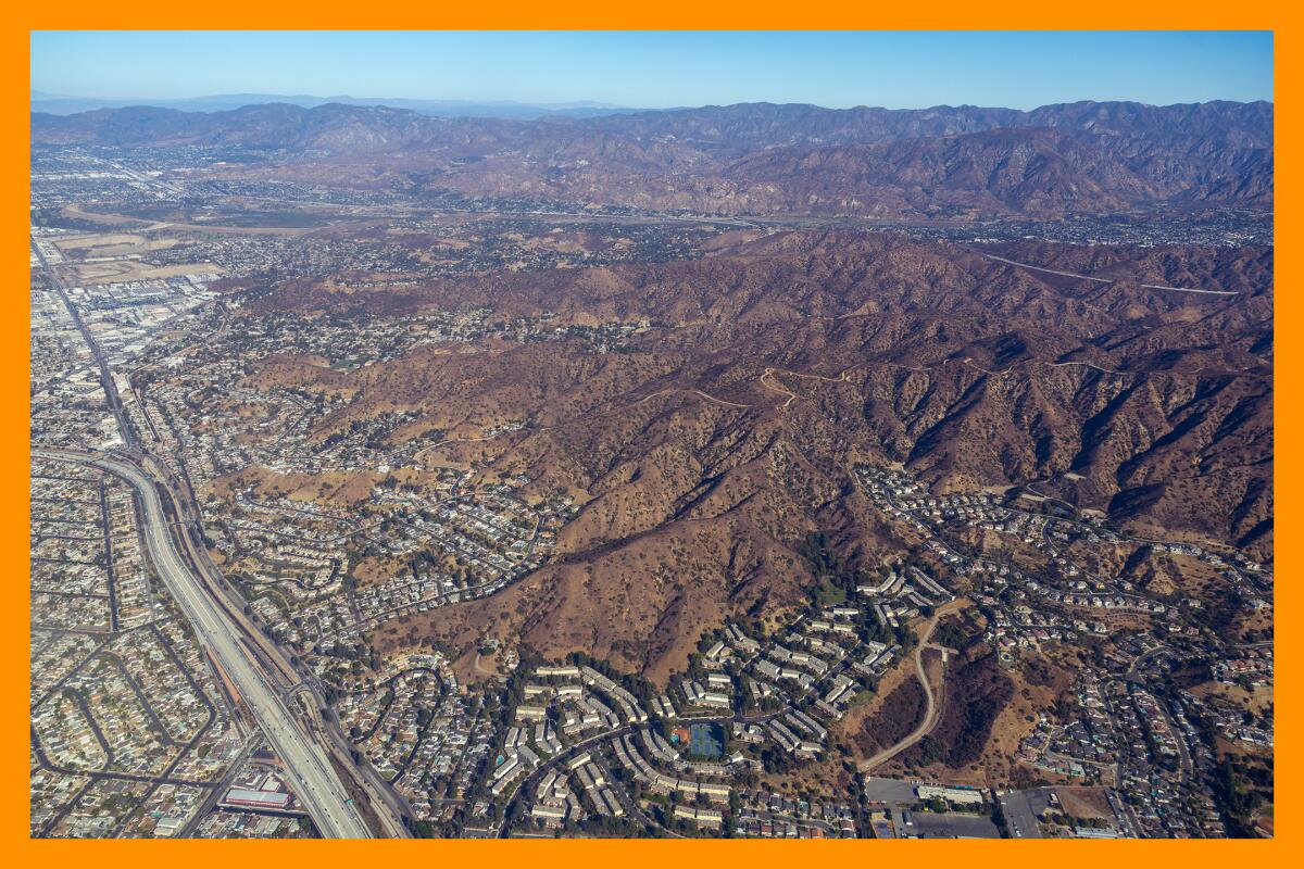 An aerial view of mountains surrounded by homes and a freeway