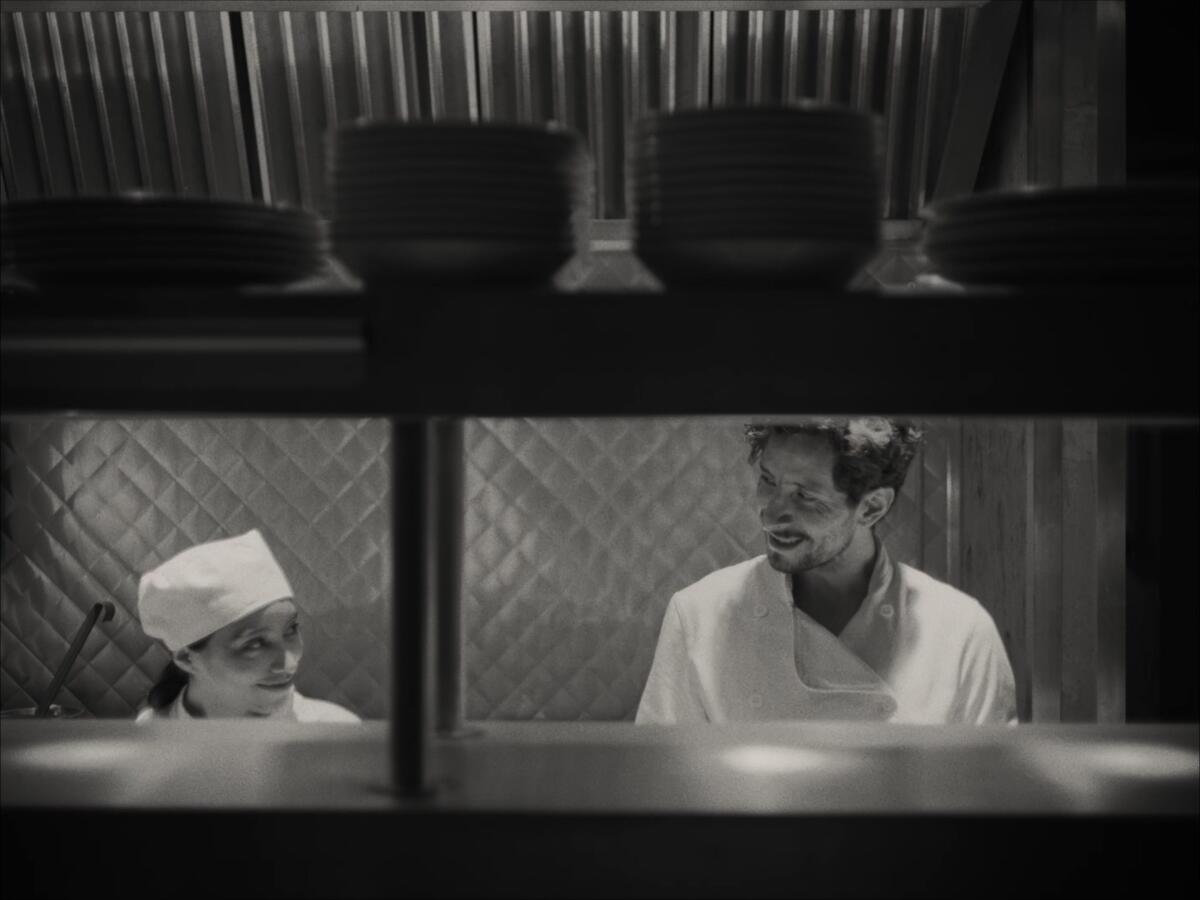 Two kitchen workers toil behind a counter.