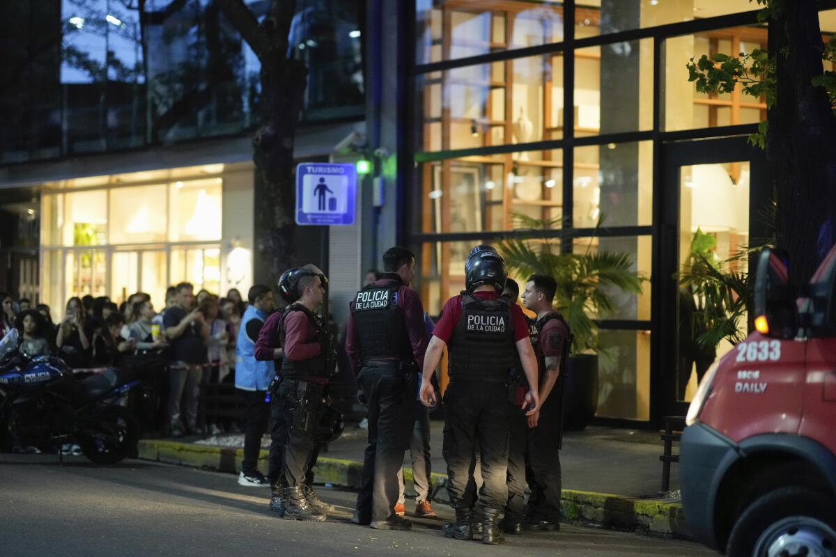 Police gather on the street at night in front of a hotel with large glass windows in Buenos Aires, Argentina