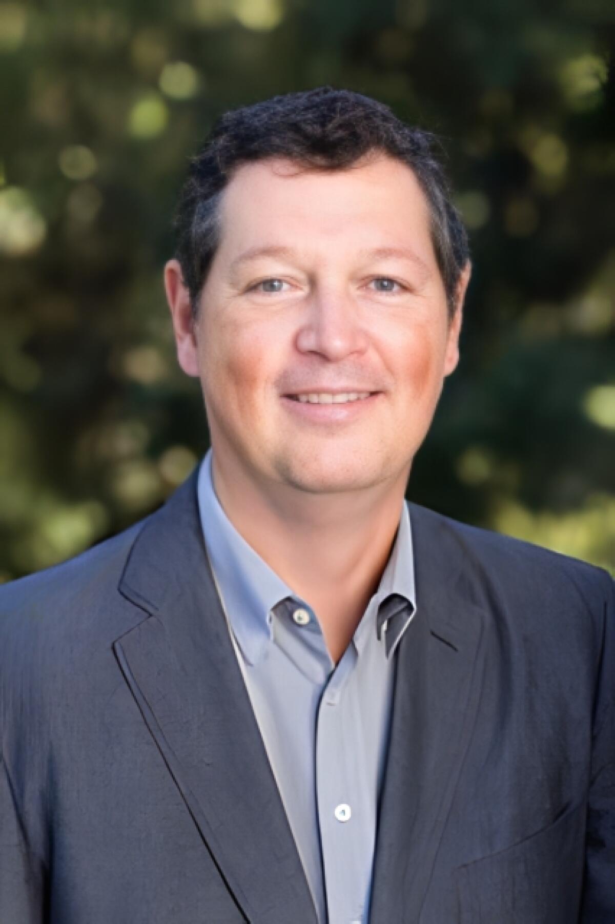 A man in a dark suit and a blue shirt.