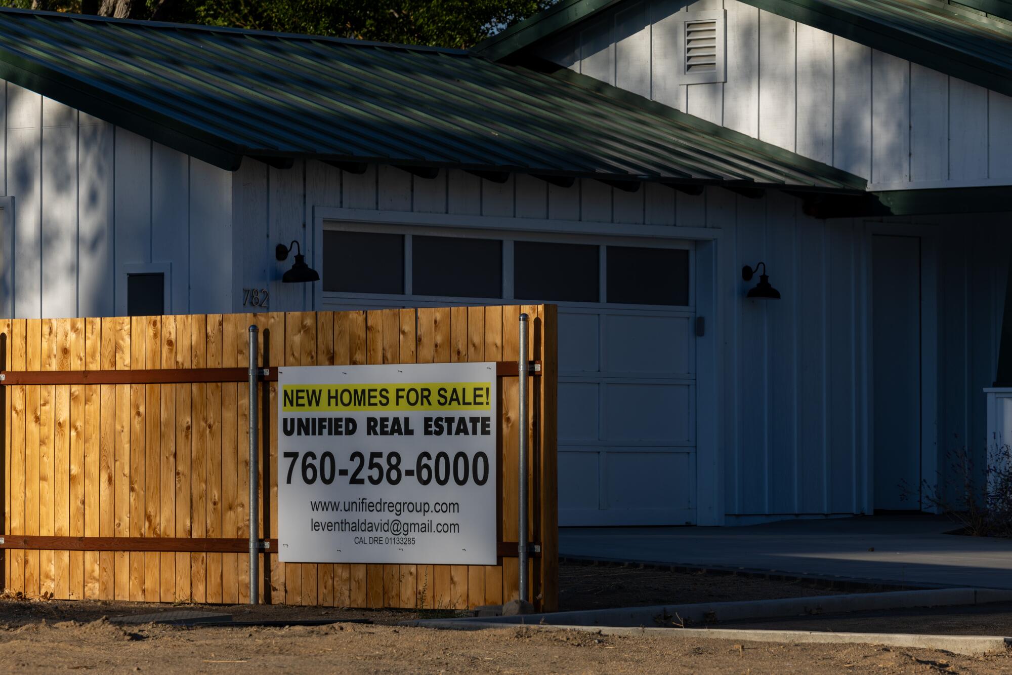 A sign on a new wooden fence advertises new homes for sale.