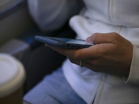 FILE - A woman looks at a hand held device on a train in New Jersey on May 18, 2021.