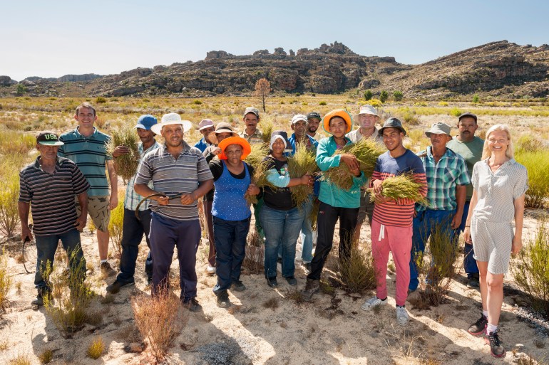 Pete and Monique Ethelston of Red Espresso standing with subsistence farmers and farmhands in rooibos plantations in the Cederberg Mountains in South Africa. [Courtesy of Red Espresso]