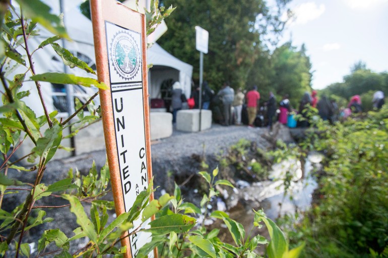 Asylum seekers wait to enter Canada at the border with the United States