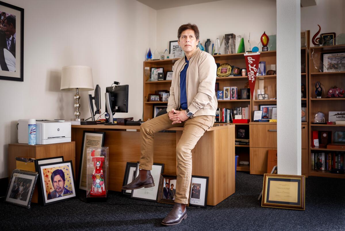 A man sits on a desk in an office.