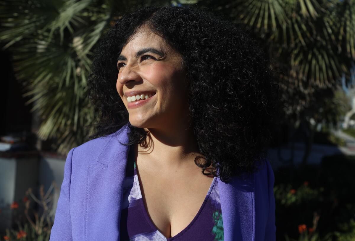 A woman smiles outdoors.