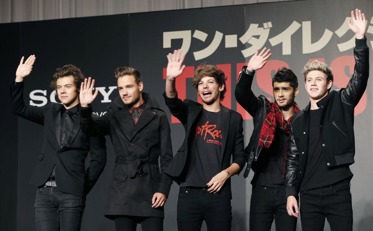 The members of One Direction wave on a red carpet.