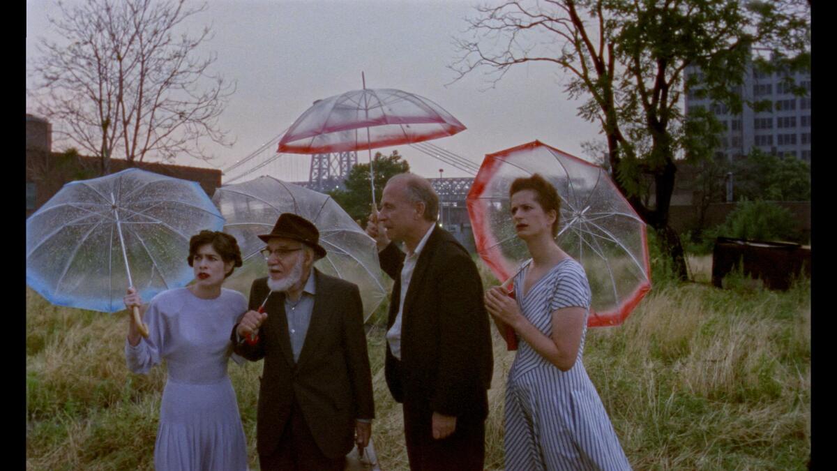 Four people standing under clear umbrellas in a field.