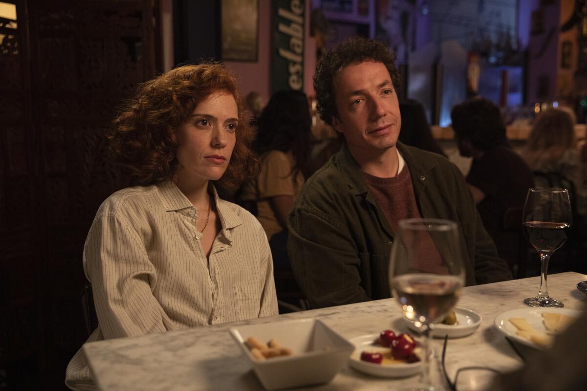 A woman and a man sit at a dinner table.