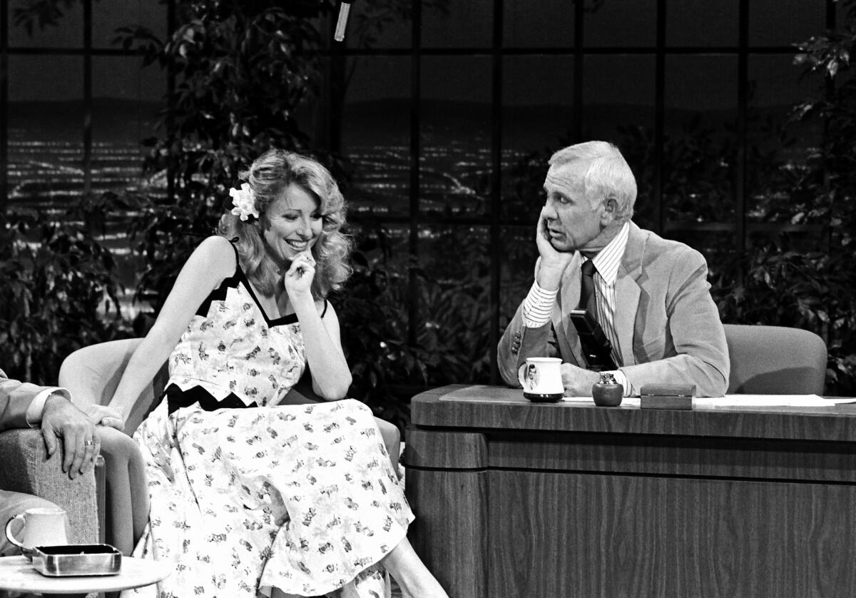 A woman is interviewed by a talk-show host.