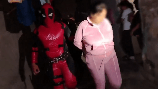 Deadpool escorts a woman through the streets during the operation