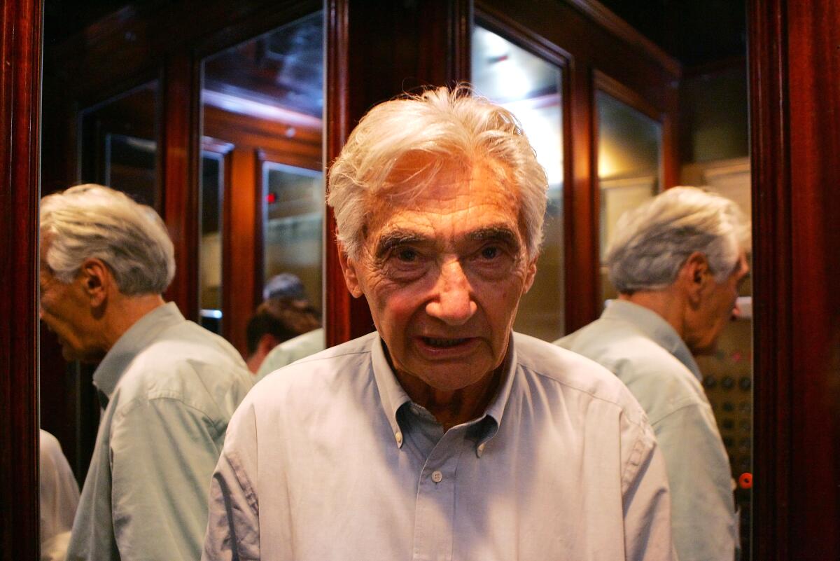 Howard Zinn stands in front of mirrors showing images of himself. 