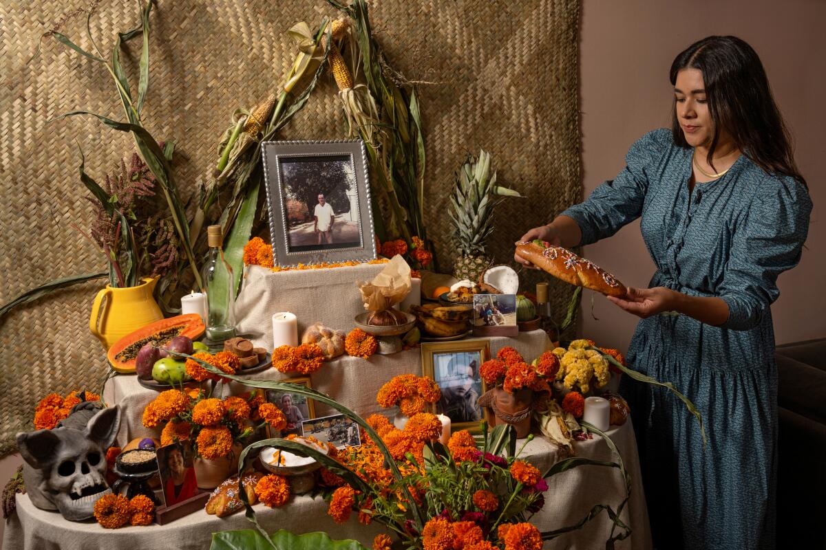 Paola Briseno Gonzalez carefully arranges the ofrenda in her home, honoring loved ones for Dia de Muertos. 