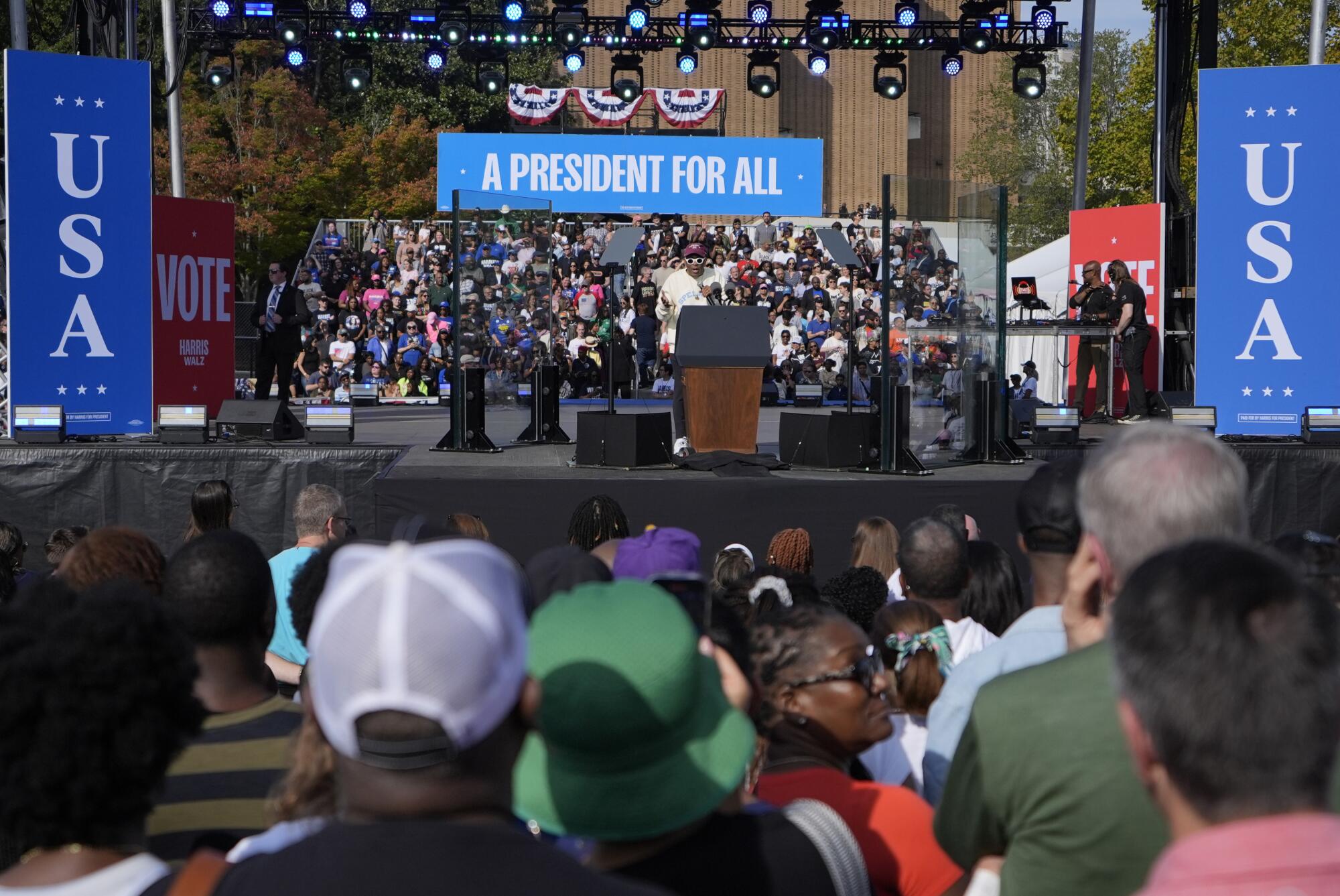 Crowdgoers watch as director Spike Lee speaks onstage at a campaign rally