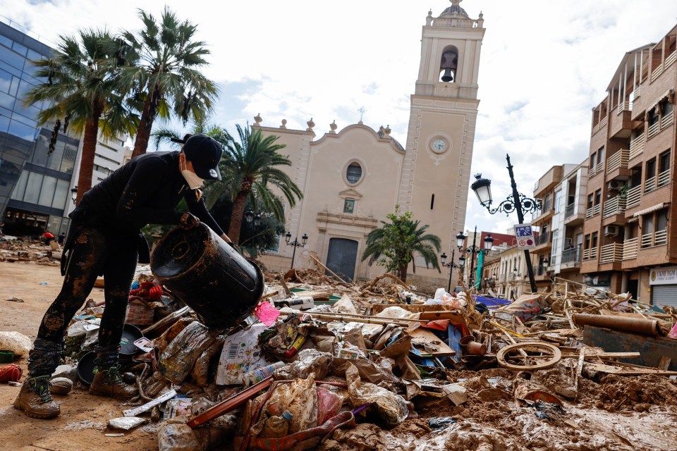 A volunteer cleans a square after flash floods in Paiporta, province of Valencia